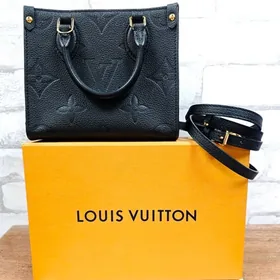 Black embossed handbag displayed with its shoulder strap