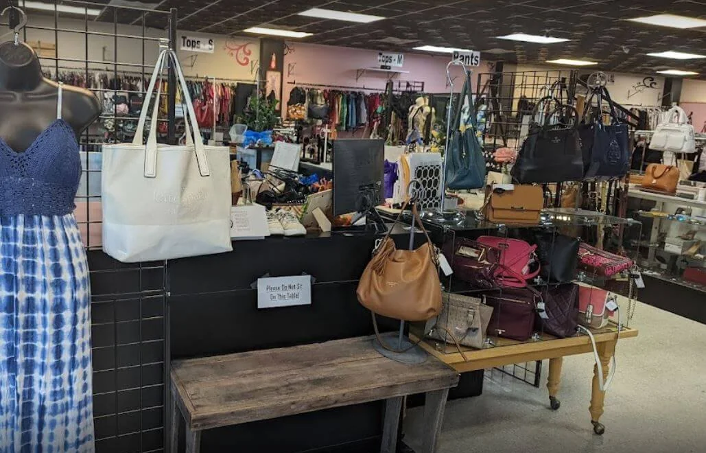 Handbags displayed on a wooden table and clothing racks inside Serendipity